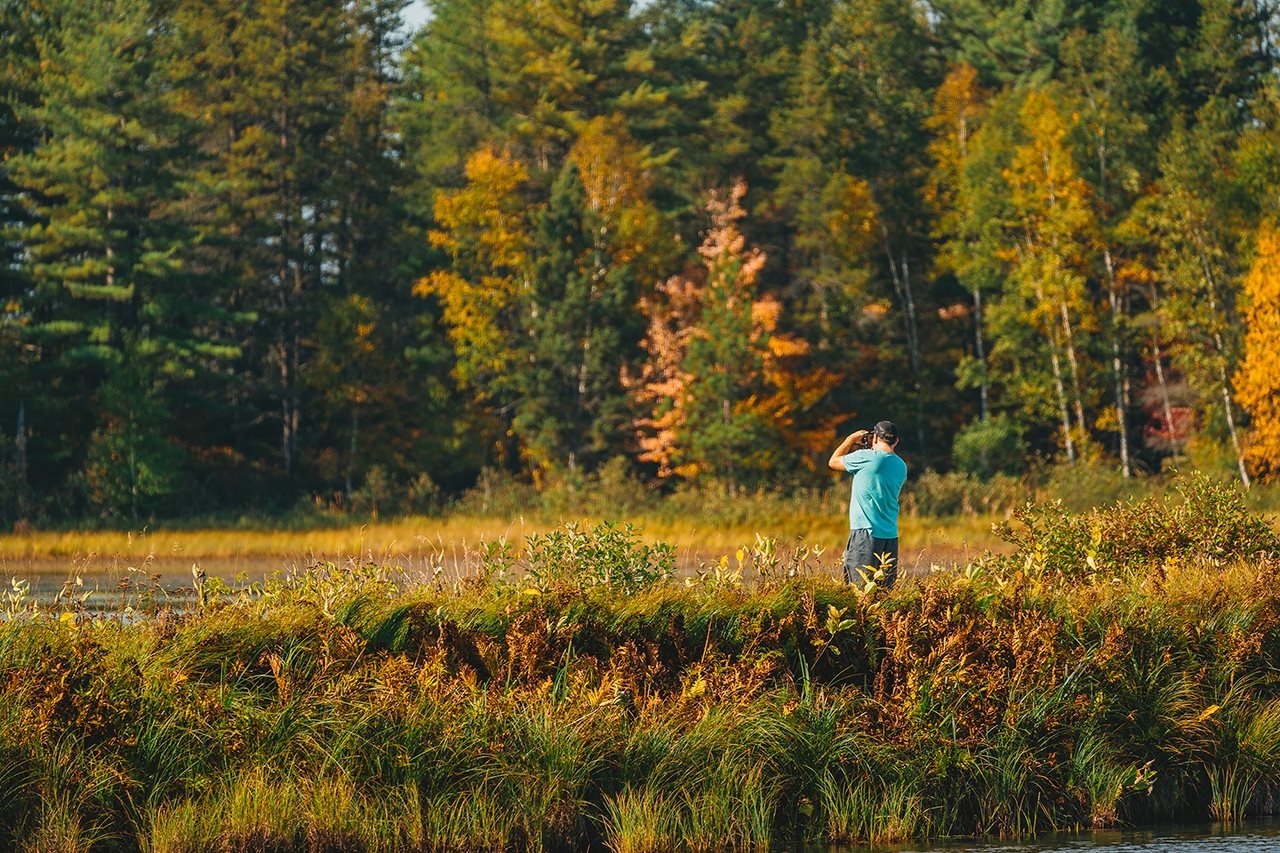 Hombre mirando a través de binoculares mientras está en El Refugio Nacional de Vida Silvestre Seney.